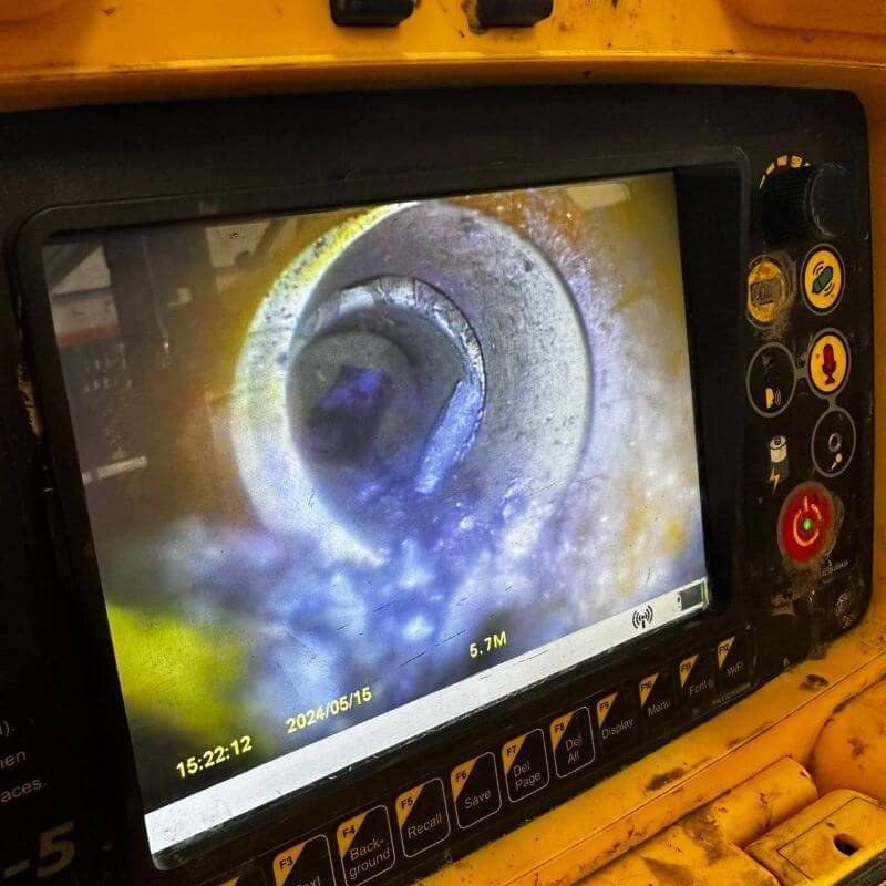 A CCTV survey monitor showing the inside of a drain pipe with a distance and time readout