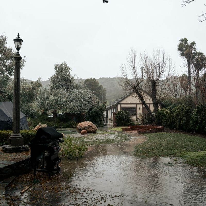 A garden and path under standing water after heavy rain because the drainage could not cope
